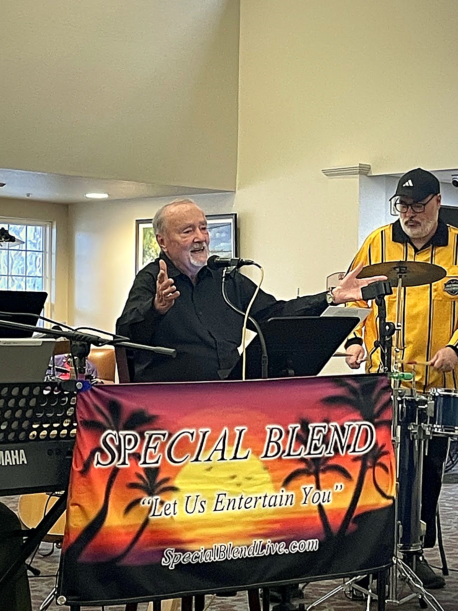 Mayo singing lead vocal behind the Special Blend sunset palm stage banner with Dan on drums